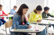 © Home-stock - Smart European school children sitting at desks, studying in classroom and writing in their copybooks, creating studious atmosphere