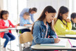 © Home-stock - Learning concept. Schoolgirl writing test or taking notes during lesson, sitting at desk in modern classroom interior