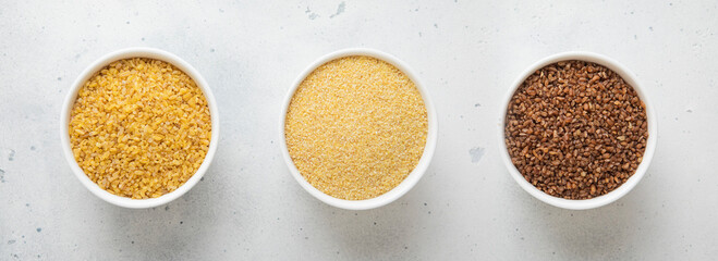 Wall Mural - Ceramic bowls with brown and yellow bulgur dry raw seeds on kitchen table.Macro.