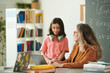 © Mediaphotos - Portrait of young girl wearing pink and talking to female teacher during consultation in school class