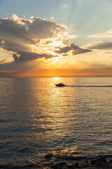Wall Mural - Picturesque sky landscape with sunset over sea and silhouette of pleasure boat in the distance. Siberian Baikal Lake in sundown light. Sunset over Small Sea on Olkhon Island beach. Natural background