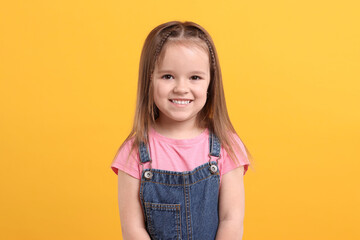 Wall Mural - Portrait of happy little girl on orange background