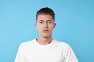 Canvas Print - Portrait of handsome young man on light blue background