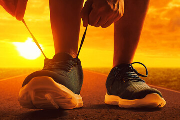 Closeup silhouette of young man tying running shoe lace on the street in the morning