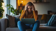 © VikaKa - A young business woman sitting in the living room of her modern apartment, holding her head in pain