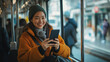 © Tahsin - Happy commuter using smartphone on public transport, enjoying connectivity during commute, cheerful passenger engaged with mobile technology, positive travel experience