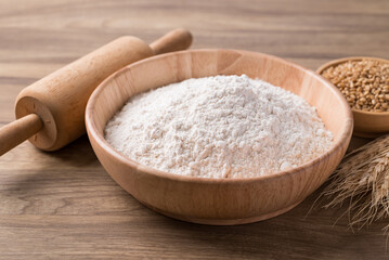 Canvas Print - Wheat flour in bowl with wheat grain and rolling pin on wooden background, Food ingredient