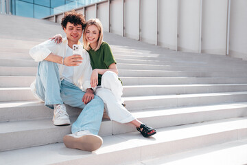 Canvas Print - Smiling beautiful woman and her handsome boyfriend. Couple in casual summer clothes. Happy cheerful family. Female and man having fun. They posing in the street in sunny day. Sit at stairs