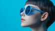 © Natali - Side profile person with blue sunglasses on blue background