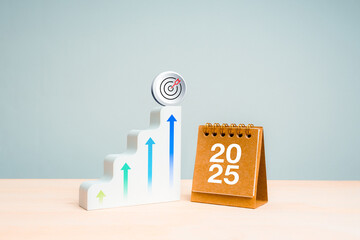 Poster - Happy new year, business target, trends, goal and success concept. 3d target icon on highest step on white modern ladder as growth graph with rising arrows and blue 2025 desk calendar on wood table.