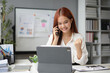 © amnaj - Excited asian businesswoman working in the office using a tablet and talking on the phone while raising her fist celebrating success