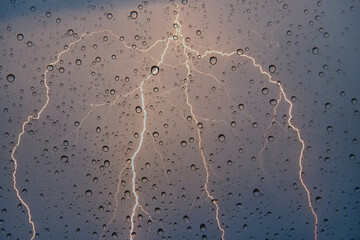 Fototapete - Lightning strike behind and raindrops on window glass