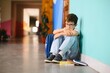 © Serhii - Young boy sitting alone with sad feeling at school. Bullying, discrimination and racism concept with copy space