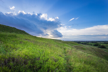 Wall Mural - Golden sunlight bathes the lush hills as clouds gather, creating a breathtaking view at dusk, inviting exploration and reflection in nature's splendor.