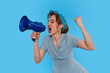 © Iryna - Woman in Blue Dress Passionately Shouting Into Megaphone Against Blue Background