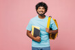© ViDi Studio - Young smiling happy cheerful smart Indian boy student wear blue t-shirt casual clothes backpack bag hold books looking camera isolated on plain pink background. High school university college concept.