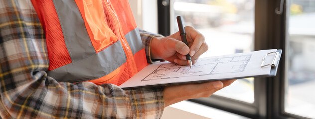 Wall Mural - Asian inspector checking structure of new property and taking note in the clipboard for review and fix the house before sell to client