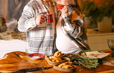 A young pregnant woman and her husband drink tea at home. Diet of a pregnant woman.