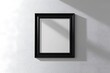 © Kanimalia - White blank frame on the wall, a mockup of a square poster or picture in a black box with a shadow and light effect on the white background