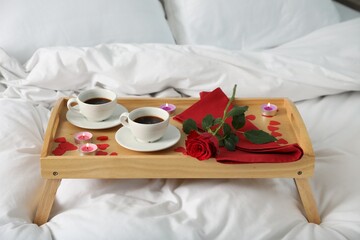 Wall Mural - Wooden tray with burning candles, rose, cups of coffee and red paper hearts on bed indoors