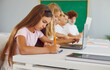 © Studio Romantic - Serious schoolgirl sitting at desk, concentrating on writing a test during a school lesson in a classroom. She is focused and engaged in studies, highlighting commitment to learning and education.