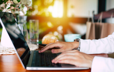 Closeup image of female hands while using laptop computer and surfing the internet, typing on keyboard, browsing. Freelancer copywriter working project, typing text, edit something