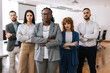 © Mediteraneo - Portrait of young CEO African American businesswoman standing with her arms crossed in front of her colleagues.