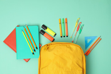 Poster - Backpack and different school supplies on turquoise background, flat lay