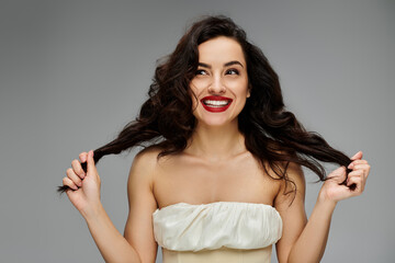 Wall Mural - Young woman poses gracefully on gray backdrop.