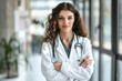 © Alberto Gonzalez  - Cheerful young nurse with a stethoscope standing in a hospital corridor.