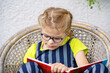 © Irina Schmidt - Little girl with eyeglasses reading book. Happy interested child learning.