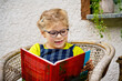 © Irina Schmidt - Little girl with eyeglasses reading book. Happy interested child learning.