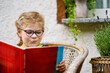 © Irina Schmidt - Little girl with eyeglasses reading book. Happy interested child learning.
