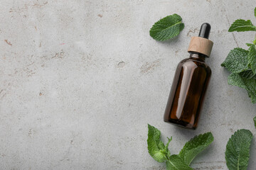 Poster - Bottle of essential oil and mint on light textured table, flat lay. Space for text