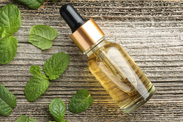 Poster - Bottle of mint essential oil and fresh leaves on wooden table, top view