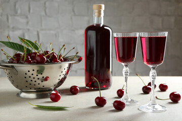 Canvas Print - Delicious cherry liqueur in glasses, bottle and fresh berries on light grey table