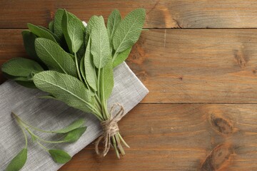 Poster - Bunch of green sage leaves on wooden table, top view. Space for text