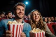 © Nena Photo - A smiling couple enjoying a movie at the cinema while holding large buckets of popcorn, capturing a moment of happiness and togetherness, reflecting a classic date night experience.