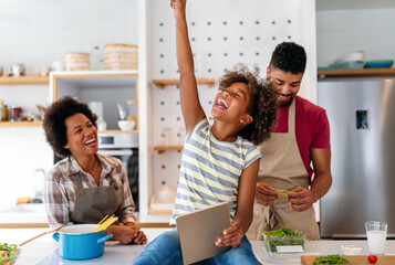 Wall Mural - Happy african family having fun with device at home. Black parents and child using digital tablet