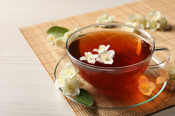 Sticker - Hot jasmine tea in cup and flowers on white wooden table