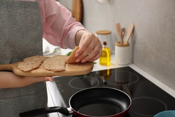 Wall Mural - Woman cooking schnitzels in frying pan on stove, closeup