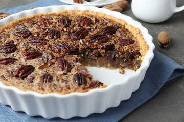 Wall Mural - Delicious pecan pie in baking dish on gray textured table, closeup