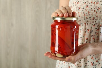 Wall Mural - Woman with jar of tasty pickled peppers indoors, closeup. Space for text