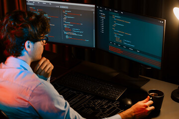 Working IT developer concentrating online software while drinking coffee on surrounded by coding application pc screens, creating program for firmware on website at neon modern office home. Gusher.
