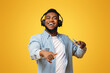 © Prostock-studio - Portrait of handsome african guy in modern headphones enjoying listening his favorite music on smartphone