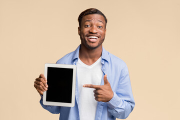 Wall Mural - Smiling Afro Man Pointing Finger At Blank Tablet Computer Screen Standing On Yellow Background In Studio. Mockup