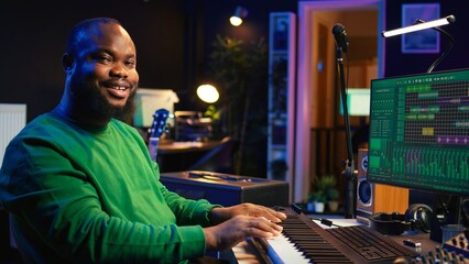 Poster - Modern producer playing piano keys to record new soundtrack, trying to produce song using midi controller electronic keyboard. Songwriter composer playing instrument notes to create tunes. Camera B.