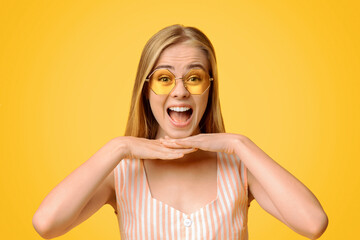 Wall Mural - Crazy Sales. Overjoyed Teen Girl In Sunglasses Resting Chin On Hands And Shouting, Posing Over Yellow Background With Copy Space