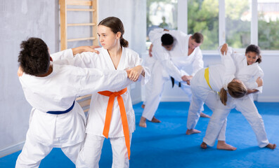 Wall Mural - Boy and girl judokas train judo in group in studio..