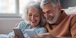 © Centric  - A senior couple relaxes in bed together, smiling as they use their smartphones, enjoying their time and connection